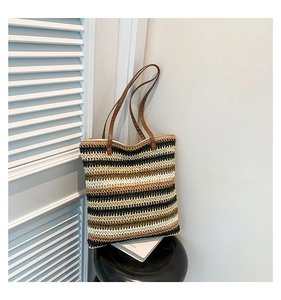 Close-up of woven striped tote bag with leather straps on a minimalist display stand