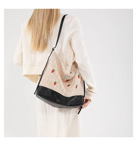 Détail de la broderie fraise sur le sac hobo tissé avec bandoulière en cuir noir