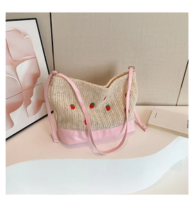 Détail du sac seau en paille avec fraises brodées et bordure en cuir rose