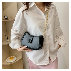 Detail of minimalist black semi-circle saddle bag with fine metal chain and square buckle