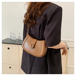 Macro detail of brown semi-moon shoulder bag with golden chain strap and smooth PU leather