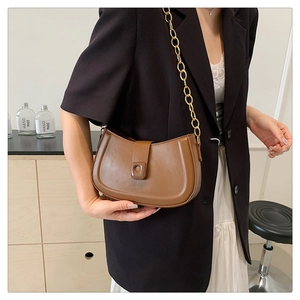 Detail of a brown crescent shoulder bag with a gold chain strap and square buckle