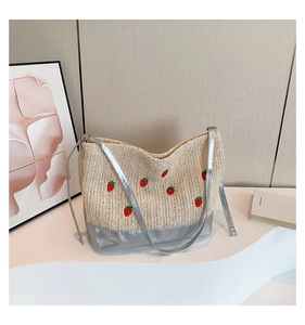 Détail d'un sac seau tissé avec broderie fraise et bandoulière argentée brillante