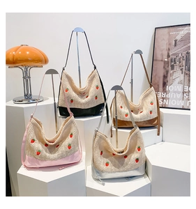 Détail de quatre sacs fourre-tout en paille avec broderie fraise et cuir