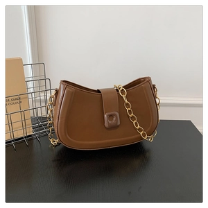 Detailed shot of brown crescent underarm bag with gold chain and premium leather texture