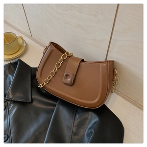 Detail of a brown crescent bag with a resin buckle on a leather jacket background