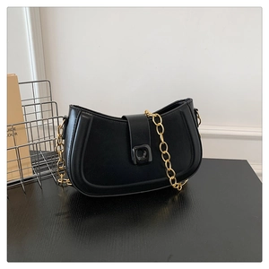 Detail of black crescent shoulder bag featuring a matte finish and bold gold chain strap