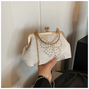 Detail of silk shell evening clutch featuring pearl heart embroidery and gold clasp