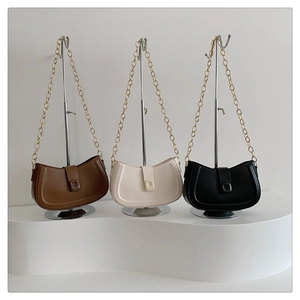 Detailed display of three moon-shaped PU leather bags with gold chain straps and metal stands