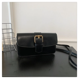 Détail du sac bandoulière en cuir noir avec boucle dorée et bandoulière minimaliste