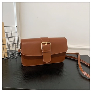 Détail d'un sac à main rétro en cuir marron avec une boucle dorée et un rabat chic