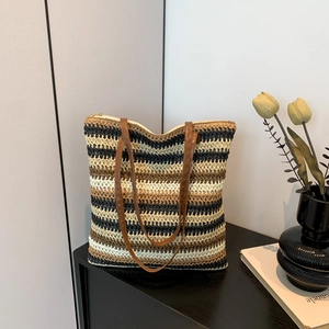 Rainbow striped woven straw tote bag with brown leather straps on a modern side cabinet