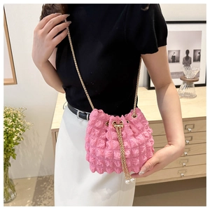 Pink bubble pleated bucket bag with gold chain and pearl drawstring on a female model