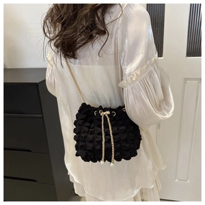 Detail of black bubble texture bucket bag with gold chain and pearl drawstring charms