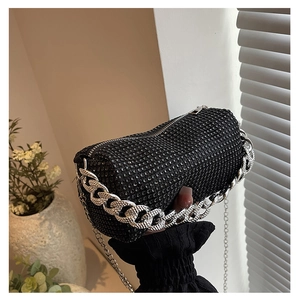 Detail of a black cylinder rhinestone handbag with silver metal chain and zipper