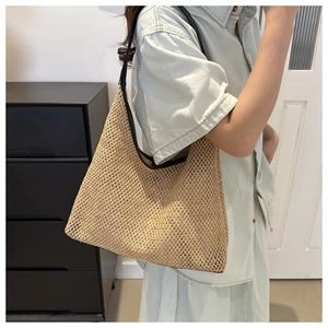 Detail of hand-woven straw shoulder bag featuring black leather trim and contrast straps