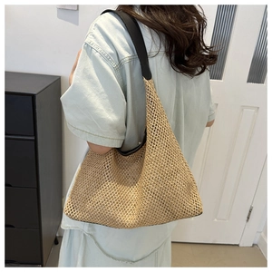 Detail of light beige hollow-out crochet straw tote bag with black leather straps