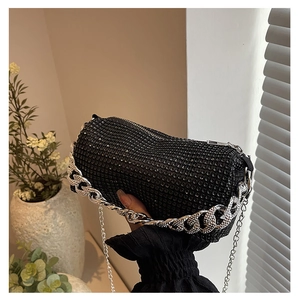 Close-up of black rhinestone cylinder bag with silver metal chain and sparkling texture
