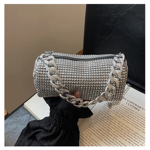 Close-up of silver rhinestone bucket bag with chunky chain handle on a book