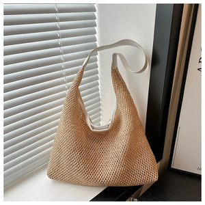 Detail of woven straw texture and cream leather strap on a large summer hobo shoulder bag