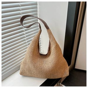 Close-up of woven straw texture and premium dark brown leather shoulder strap