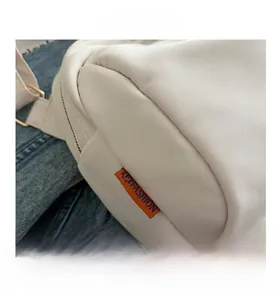 Detail of white Oxford shell bag featuring orange Fashion label and metal zipper