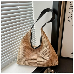 Detail of hand-woven straw tote with premium black leather shoulder strap and fine texture