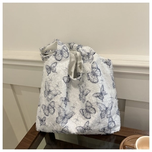 Detailed close-up of white tote bag with blue butterfly prints and fuzzy texture fabric