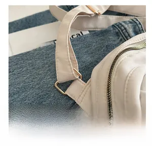 Detail of cream nylon bag with gold metal buckles and adjustable strap texture