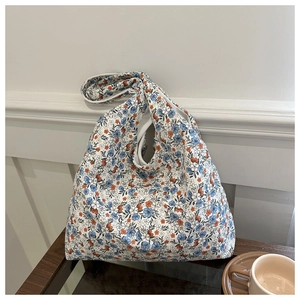 Detail of floral canvas tote bag showing single strap design on a wooden table