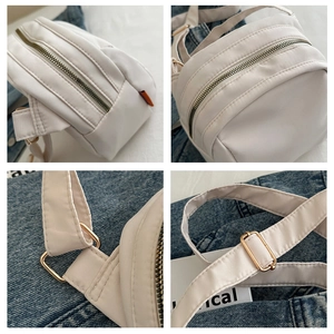Close-up of white nylon shell bag showing golden metal zippers and hardware details