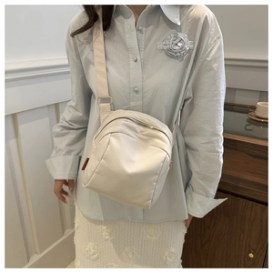 Detailed view of cream nylon shell crossbody bag with adjustable wide strap for women