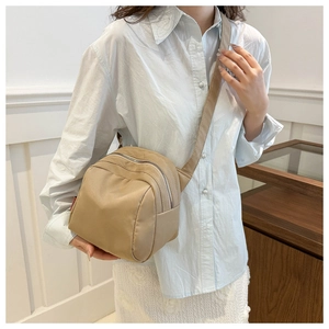 Detail of khaki nylon crossbody bag with double zippers and wide adjustable strap