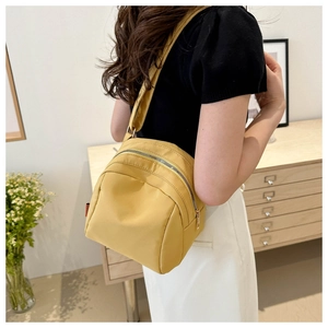Detail of a bright yellow nylon crossbody bag featuring multi-layer metal zippers