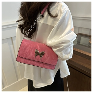Detailed close-up of pink pleated underarm bag with silver butterfly and chain strap