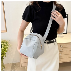 Adjustable light blue nylon crossbody bag shown in a lifestyle home setting with flowers