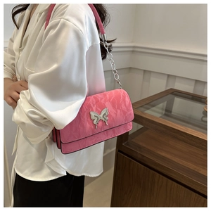 Close-up of pink shoulder bag with pleated texture and silver butterfly buckle detail
