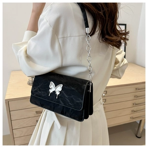 Close-up of black pleated faux leather bag with silver butterfly metal buckle and chain