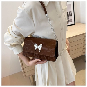 Detail of dark brown crinkled leather shoulder bag featuring a silver butterfly clasp