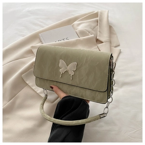 Detail of light green rectangular bag with silver butterfly emblem and metal chain handle