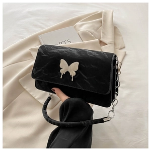 Close-up of black pleated underarm bag featuring silver butterfly buckle and chain strap