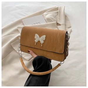 Detail of caramel PU leather bag with large marble-textured white butterfly and silver chain