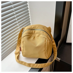 Detail of mustard yellow nylon shell bag with red label and golden adjustable buckle