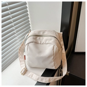 Close-up of cream canvas shell bag with zipper and adjustable shoulder strap