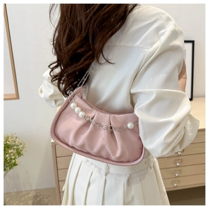 Detailed shot of pink pleated underarm bag with decorative pearl chain and metal strap