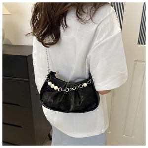 Detail of black pleated crescent bag with decorative pearl and flower metal chain