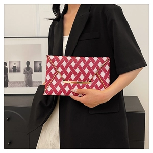 Détail de la pochette enveloppe tissée rouge et blanc avec garniture dorée par un modèle