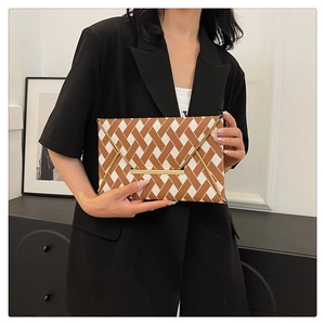 Détail d'une pochette enveloppe tissée marron et blanc avec un fermoir en métal doré chic