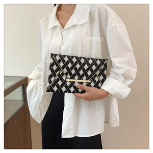 Détail d'une pochette de soirée au motif géométrique noir et blanc et fermoir doré
