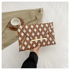 Détail d'une pochette enveloppe à motif tissé marron et blanc avec fermoir doré
